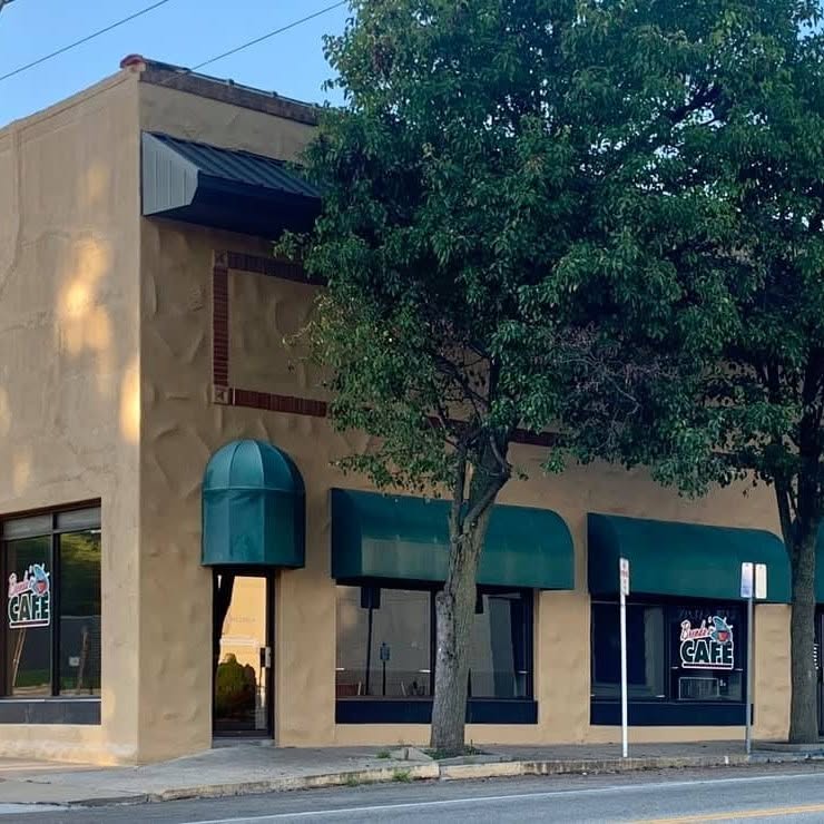 The front of Brenda's Cafe on West Broadway Street, cream stucco with dark green awnings