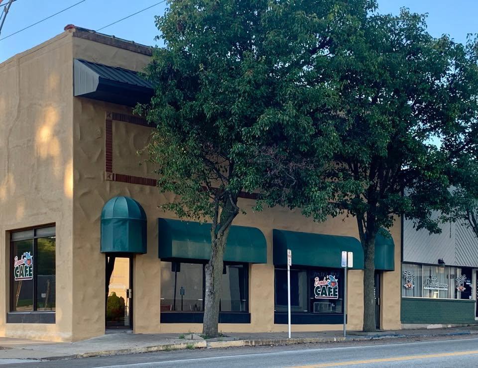 The front of Brenda's Cafe on West Broadway Street in Bolivar, cream stucco with dark green awnings and a neon window sign